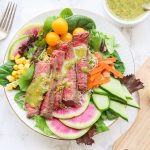 This spring steak salad with homemade carrot and cilantro chimichurri vinaigrette dressing uses crisp spring vegetables and tops them with tender juicy steak pieces and a drizzle of fresh herb chimichurri sauce. Colorful vibrant vegetables combined with high-quality steak choices from our sponsor PRE Brands make this salad a standout showstopper.