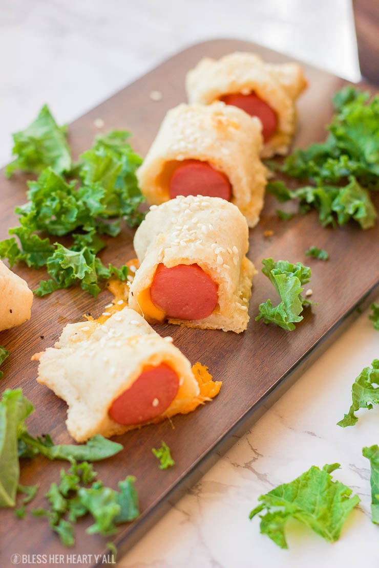 This gluten-free pigs in a blanket recipe wraps sausages or hotdogs in gooey cheddar cheeses and a doughy and perfectly crisp golden brown outer crust made from an easy combination of gluten free flours. www.BlessHerHeartYall.com