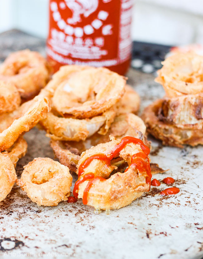These Honey + Sriracha Onion Rings are crispy, crunchy, and fresh. The spicy Sriracha chili paste is added for some sizzle and fresh honey {straight from the hills of Tennessee y’all} is paired with it to tone down the fire a bit and add some sweet afterthoughts. These sweet and spicy onion rings are incredibly easy to make and take just minutes to find your plate! www.ahotsouthernmess.com