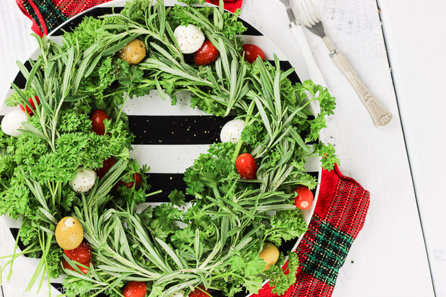 This holiday olive wreath is a festive holiday appetizer that is not only easy to put together, put easily adaptable to the party-goers likes and needs. Plate your favorite herbs underneath tasty mozzarella cheese, sweet tomatoes, and your favorite olives. Sprinkle cracked pepper and a delicious balsamic drizzle to finish! www.blessherheartyall.com