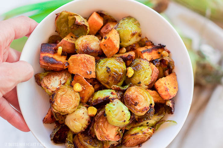 This healthy roasted sweet potato brussel sprout hash is a simple fall treat that drizzles on a light layer of olive oil, garlic, and cumin before roasting. The vegan and gluten-free recipe produces perfectly golden baked sweet potato pieces surrounded by fresh spiced corn kernels and crisp and tender cooked brussel sprouts. 