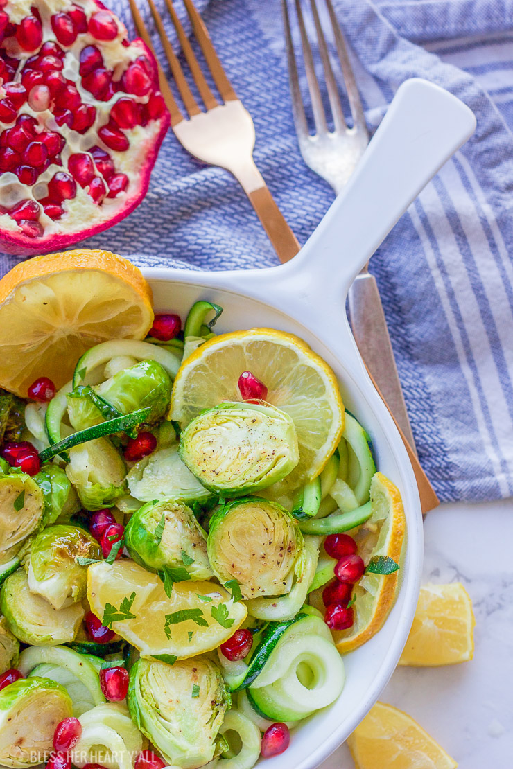 This lemon garlic roasted brussel sprouts + zucchini recipe is a clean, crisp, savory vegetable dish that is not only healthy but a gorgeous and easy addition to any meal! Lemon, honey, and garlic flavors coat the roasted brussel sprouts, zucchini noodles, and pomegranate arils for a colorful fresh salad.