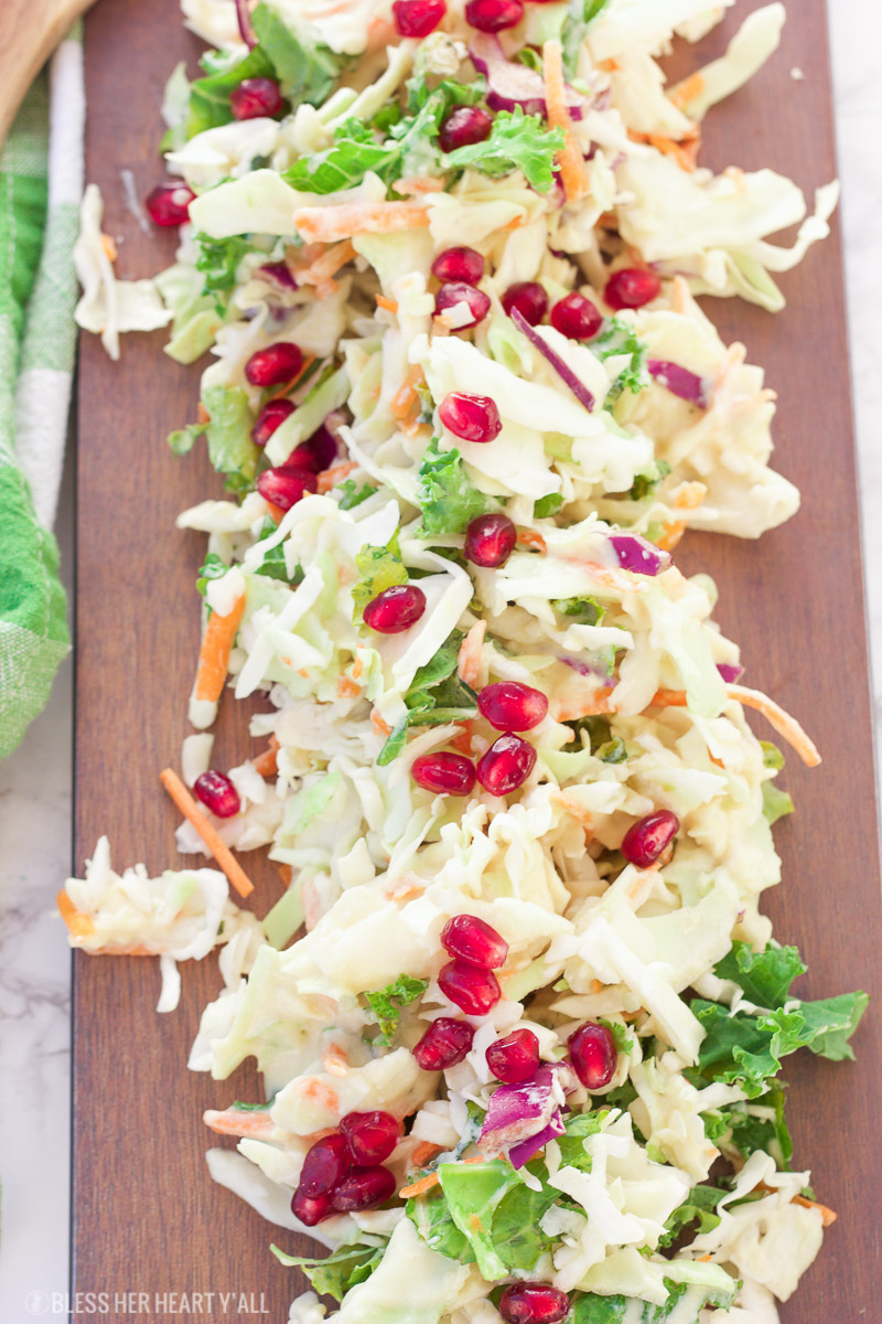 A healthy winter pomegranate cole slaw that's creamy and fresh and ready in under 5 minutes! The recipe uses a greek yogurt sauce as a base and then adds in apple slices, kale, lemon, and pomegranate to create a sweet and mellow sauce drizzled over crisp shredded cabbage and seasonal veggies.