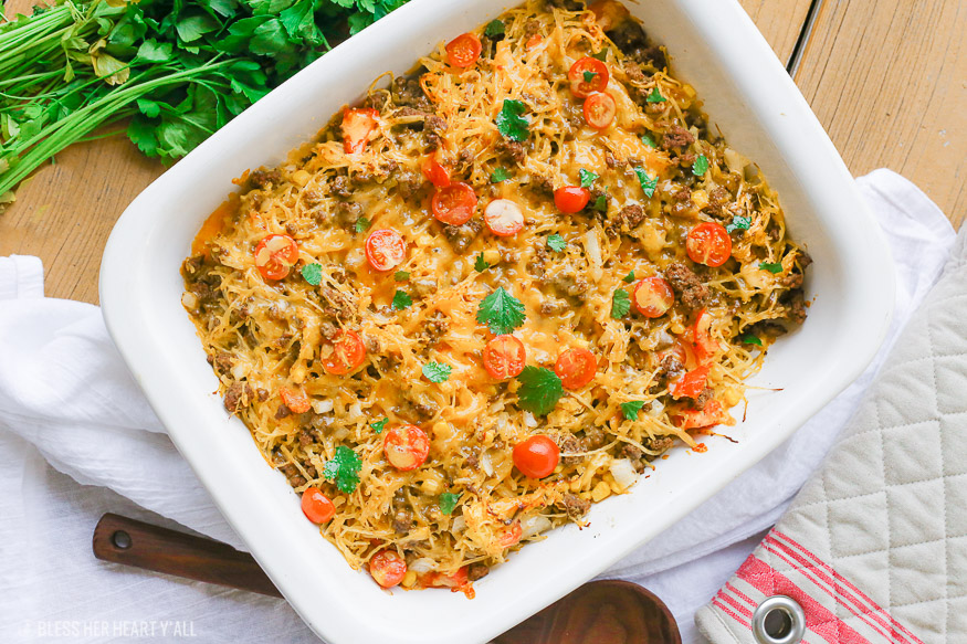 Spaghetti squash taco bake roasts fluffy spaghetti squash and melts it into seasoned ground meat, tomatoes, onion, corn, beans, and tops it off with melty cheese and fresh cilantro for the perfect healthy taco-inspired casserole!