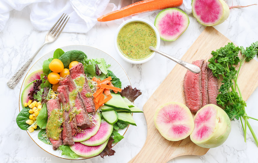 This spring steak salad with homemade carrot and cilantro chimichurri vinaigrette dressing uses crisp spring vegetables and tops them with tender juicy steak pieces and a drizzle of fresh herb chimichurri sauce. Colorful vibrant vegetables combined with high-quality steak choices from our sponsor PRE Brands make this salad a standout showstopper. 