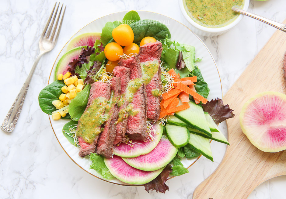 This spring steak salad with homemade carrot and cilantro chimichurri vinaigrette dressing uses crisp spring vegetables and tops them with tender juicy steak pieces and a drizzle of fresh herb chimichurri sauce. Colorful vibrant vegetables combined with high-quality steak choices from our sponsor PRE Brands make this salad a standout showstopper.