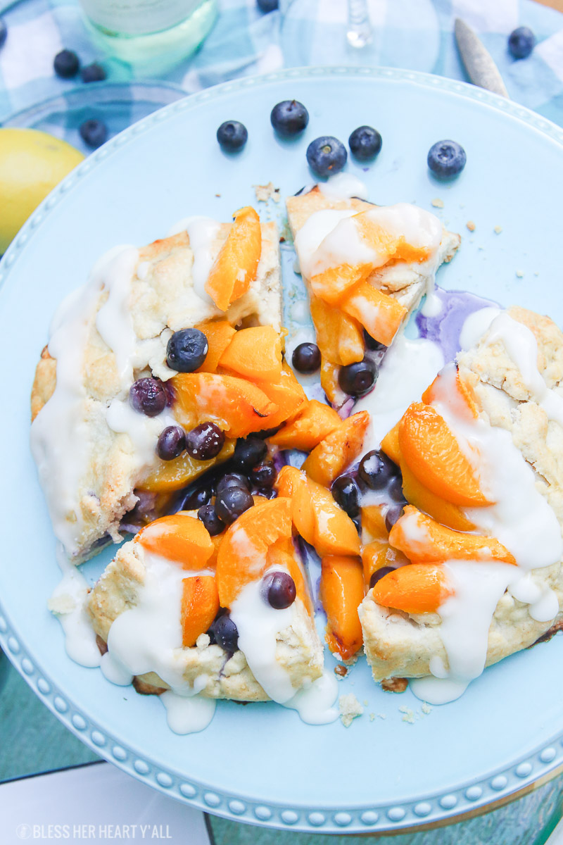 This peach blueberry galette combines peach slices and fresh blueberries in a sweet juicy sauce and then spreads it inside a doughy sugar-lined crust and bakes it all to golden perfection. This gluten free tart is drizzled in a light lemon glaze and is the perfect summer snack to enjoy outside on the back deck with a chilled bottle of white wine!