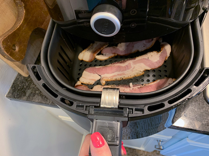 Insert of the air fryer basket with the bacon in the air fryer.