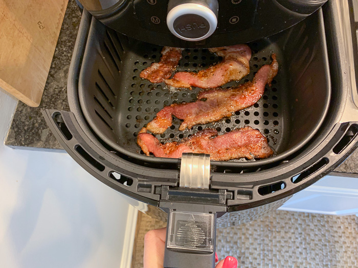 Check ing air fryer bacon for doneness.