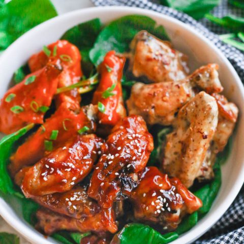 air fryer chicken wings with three different sauces in white bowl with vegetable greens