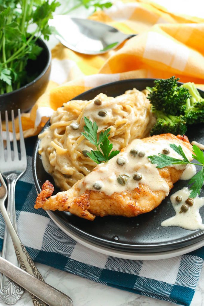 creamy instant pot chicken piccata in black bowl with pasta
