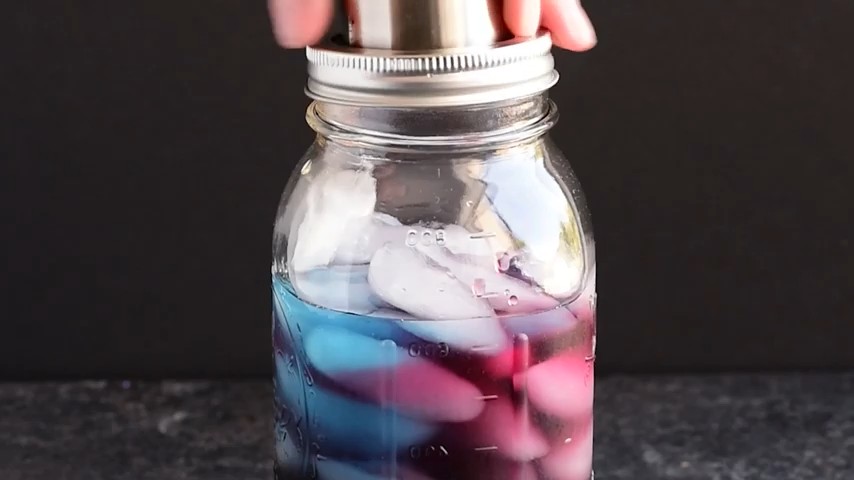 blue and red colors fading in a cocktail jar to form a purple rain drink