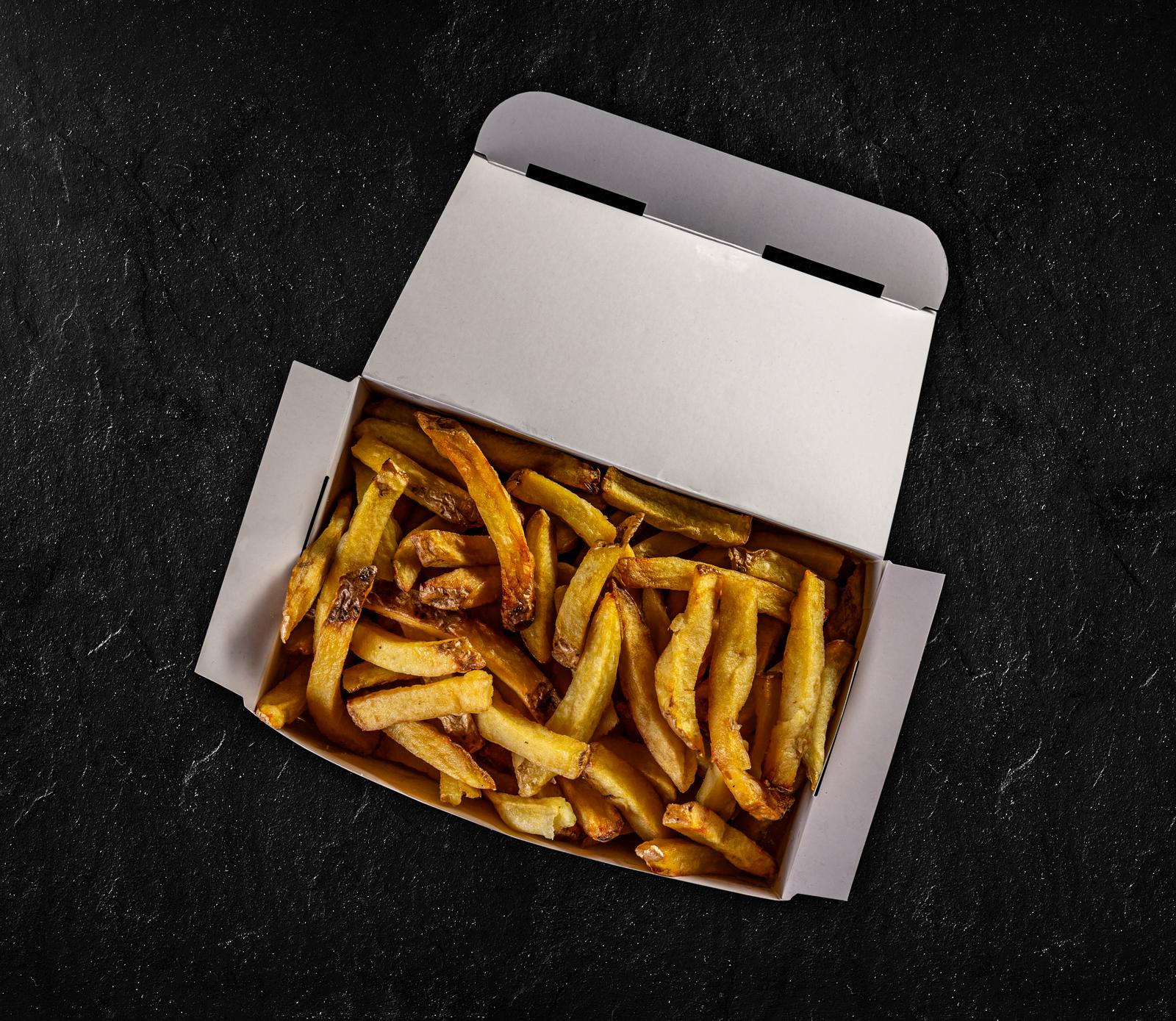 French fries in paper box on black background